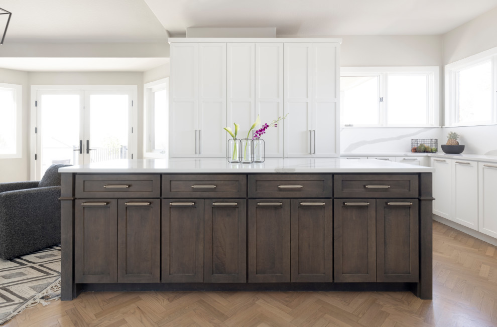 Example of a large transitional l-shaped light wood floor enclosed kitchen design in Denver with a double-bowl sink, shaker cabinets, gray cabinets, quartz countertops, white backsplash, quartz backsplash, stainless steel appliances, two islands and white countertops