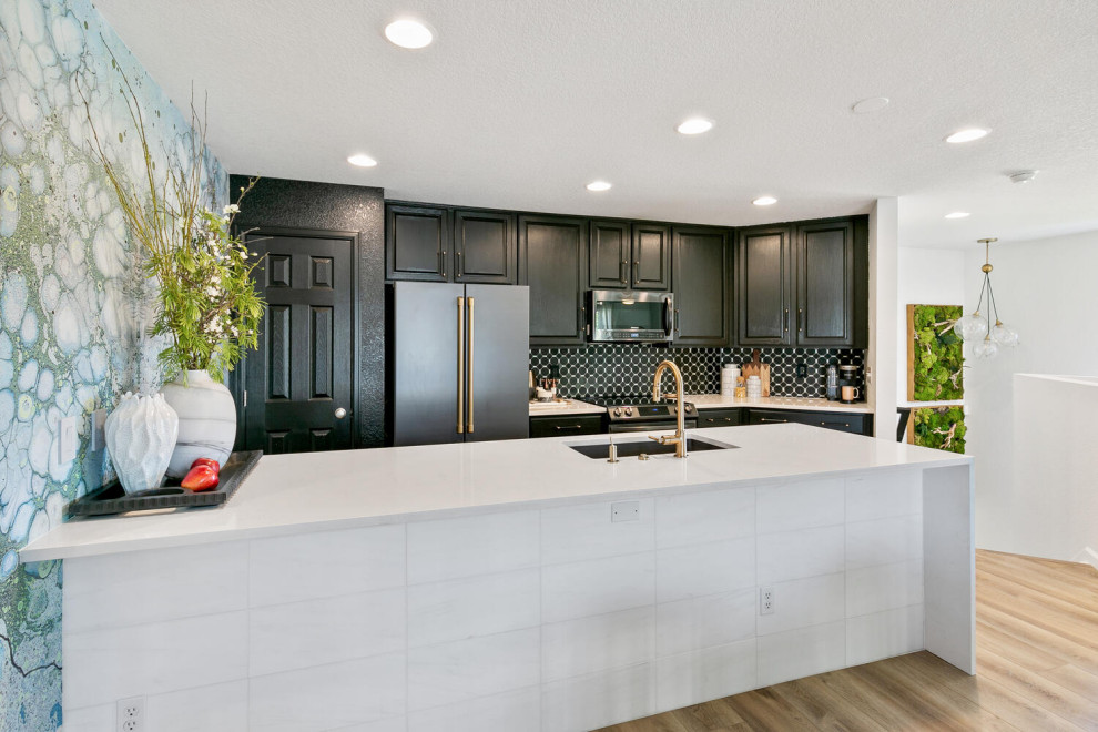 Example of a mid-sized transitional l-shaped medium tone wood floor and brown floor open concept kitchen design in Denver with an undermount sink, black cabinets, quartz countertops, black backsplash, marble backsplash, stainless steel appliances, an island and white countertops