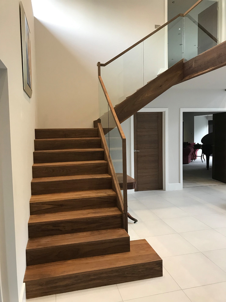 Inspiration for a mid-sized contemporary wood l-shaped staircase in Hampshire with wood risers and glass railing.