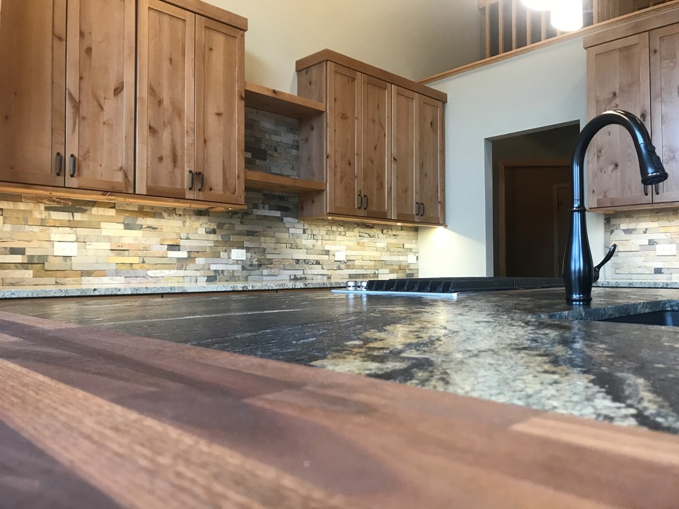 Inspiration for a large rustic l-shaped medium tone wood floor and brown floor home design remodel in Chicago with an undermount sink, shaker cabinets, medium tone wood cabinets, granite countertops, green backsplash, slate backsplash, stainless steel appliances, an island and black countertops