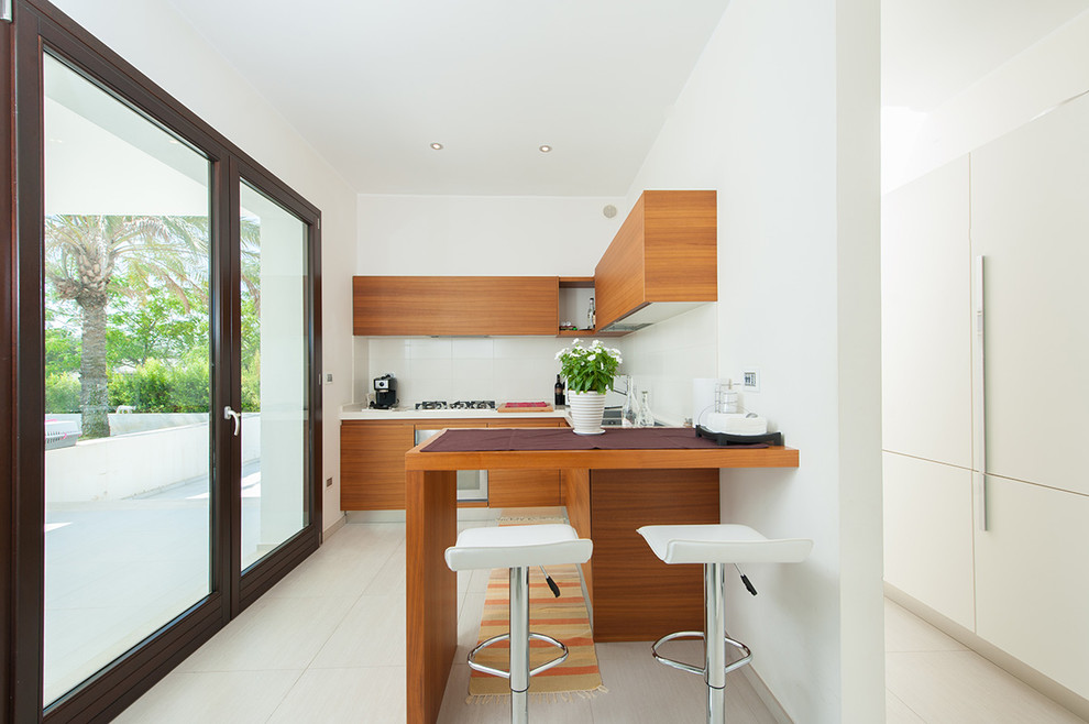 This is an example of a small contemporary u-shaped open plan kitchen in Bari with flat-panel cabinets, white splashback, a peninsula, a double-bowl sink, light wood cabinets, stainless steel appliances and white floor.