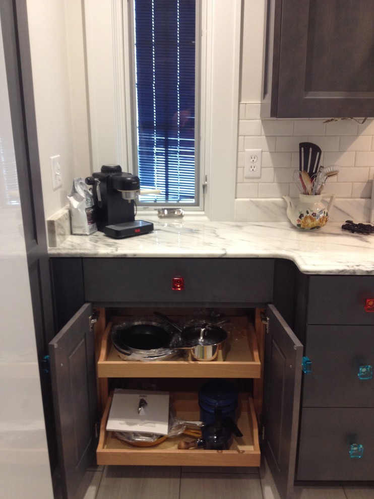 Inspiration for a large transitional u-shaped porcelain tile eat-in kitchen remodel with a farmhouse sink, flat-panel cabinets, gray cabinets, marble countertops, white backsplash, ceramic backsplash, white appliances and no island