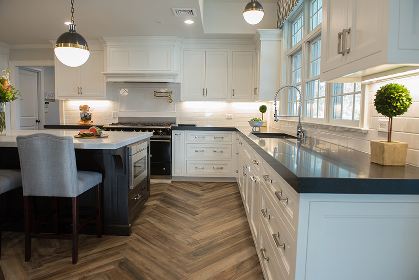 This is an example of a transitional eat-in kitchen in New York with white cabinets, marble benchtops, white splashback, black appliances, porcelain floors and with island.
