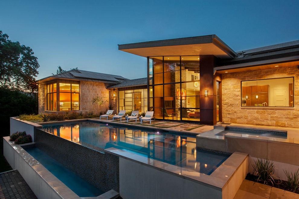 Inspiration for a large contemporary backyard rectangular infinity pool in Austin with a hot tub and concrete pavers.