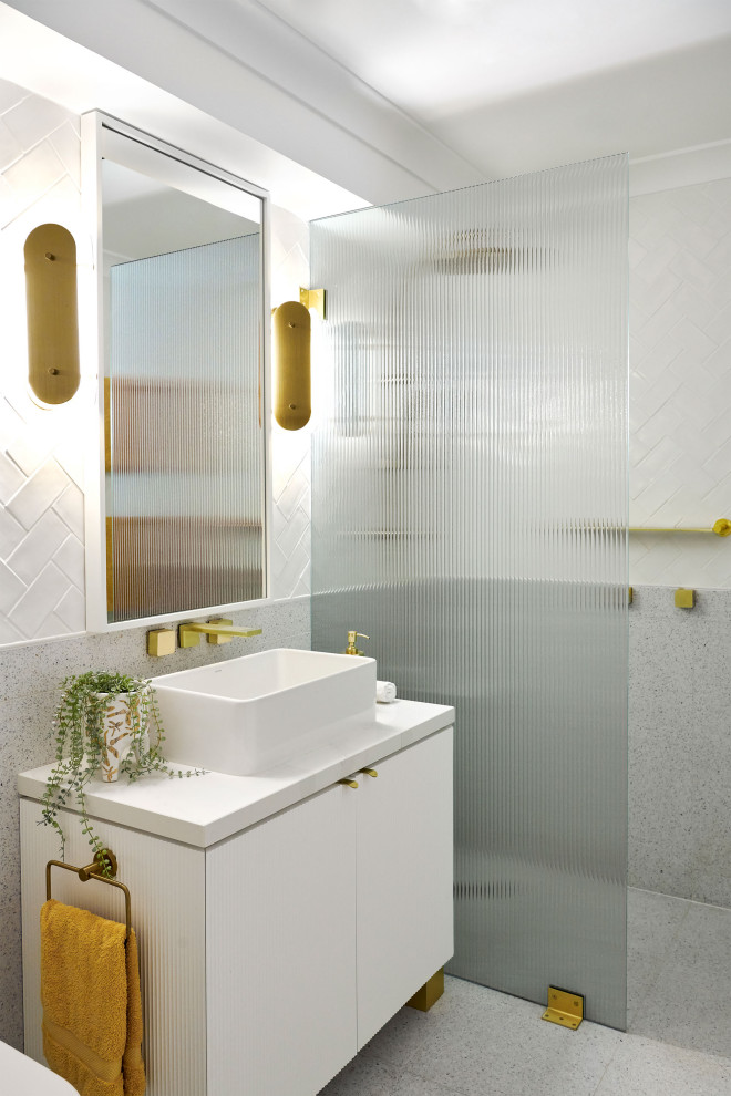 Design ideas for a mid-sized eclectic kids bathroom in Sydney with furniture-like cabinets, white cabinets, an open shower, a two-piece toilet, white tile, subway tile, white walls, terrazzo floors, a vessel sink, engineered quartz benchtops, white floor, an open shower, white benchtops, a single vanity, a freestanding vanity and panelled walls.