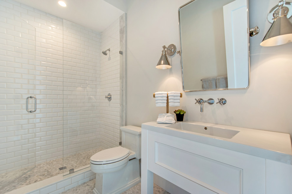 Photo of a transitional bathroom in Orange County with white cabinets, an alcove shower, white tile, subway tile, white walls, mosaic tile floors, an integrated sink, grey floor, a hinged shower door, white benchtops and recessed-panel cabinets.