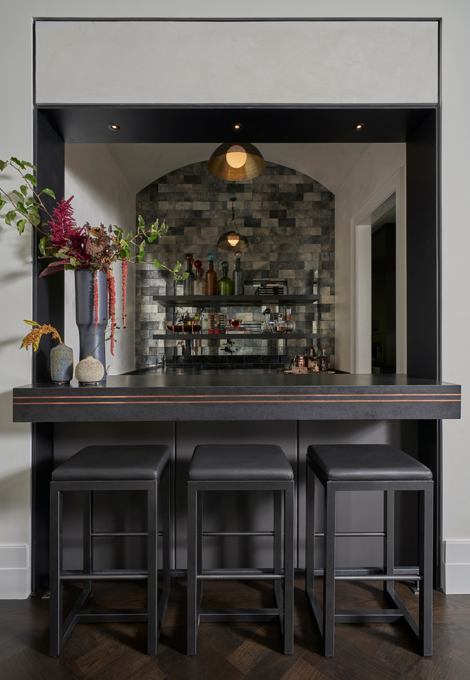 Design ideas for a transitional seated home bar in Chicago with dark hardwood floors, black benchtop, open cabinets and multi-coloured splashback.