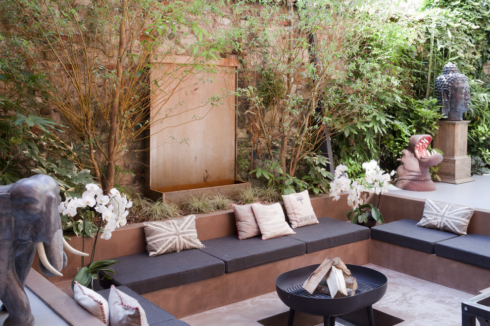 Inspiration for an eclectic backyard patio in Milan with a fire feature, concrete slab and no cover.