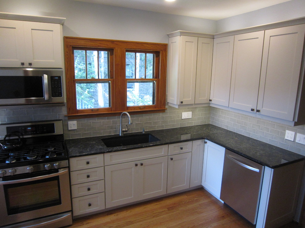 Eat-in kitchen - mid-sized transitional l-shaped light wood floor eat-in kitchen idea in Chicago with an undermount sink, shaker cabinets, gray backsplash, subway tile backsplash, stainless steel appliances, no island, white cabinets and granite countertops