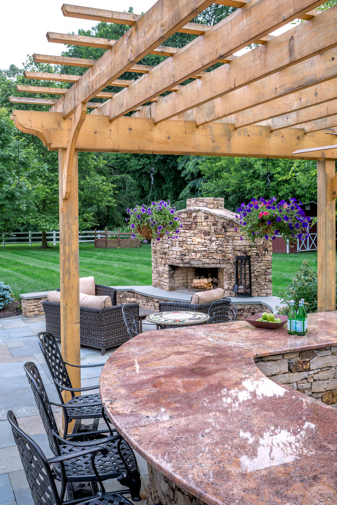 Country patio in Baltimore with a fire feature, natural stone pavers and a pergola.