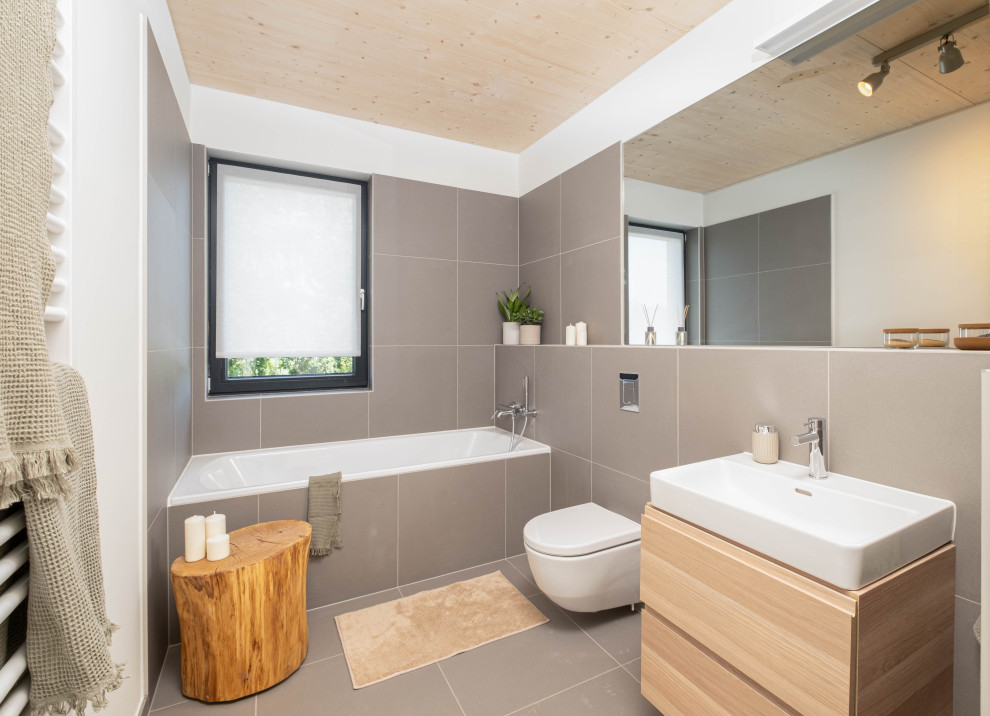 Стильный дизайн: большая главная, серо-белая ванная комната в скандинавском стиле с плоскими фасадами, светлыми деревянными фасадами, ванной в нише, душем в нише, инсталляцией, серой плиткой, цементной плиткой, серыми стенами, полом из цементной плитки, серым полом, тумбой под одну раковину, подвесной тумбой и деревянным потолком - последний тренд