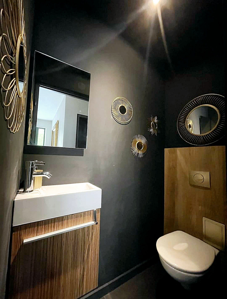 Foto på ett funkis toalett, med en vägghängd toalettstol, svarta väggar, ett väggmonterat handfat och svart golv