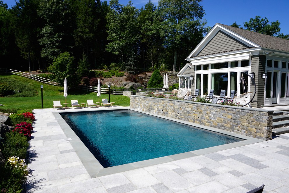This is an example of a mid-sized modern backyard rectangular lap pool in New York with natural stone pavers.