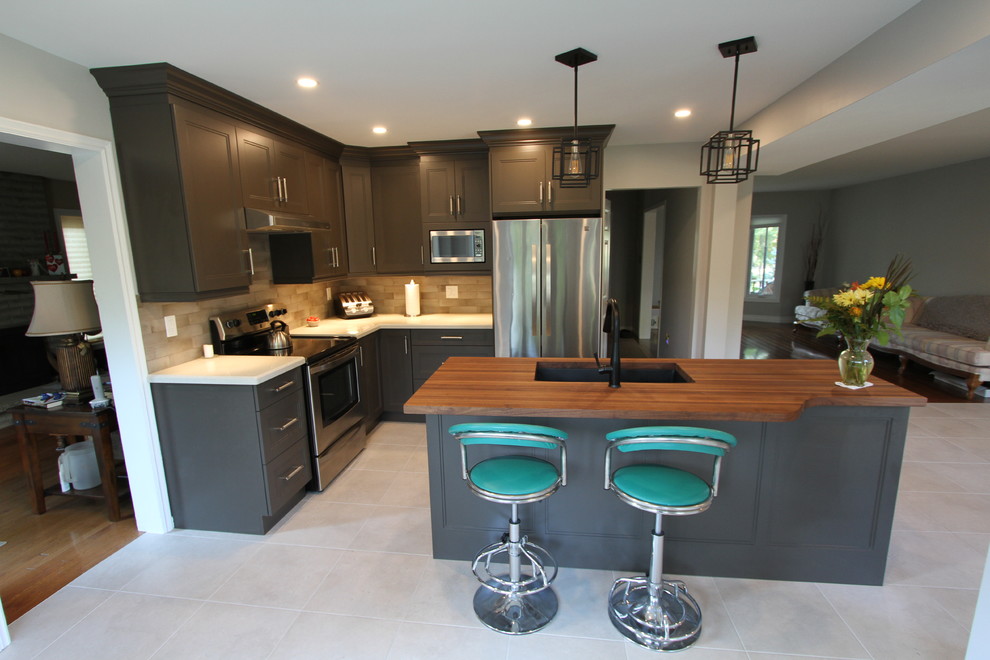 Inspiration for a mid-sized contemporary l-shaped eat-in kitchen in Toronto with an undermount sink, recessed-panel cabinets, brown cabinets, wood benchtops, grey splashback, porcelain splashback, stainless steel appliances, porcelain floors, with island, grey floor and brown benchtop.
