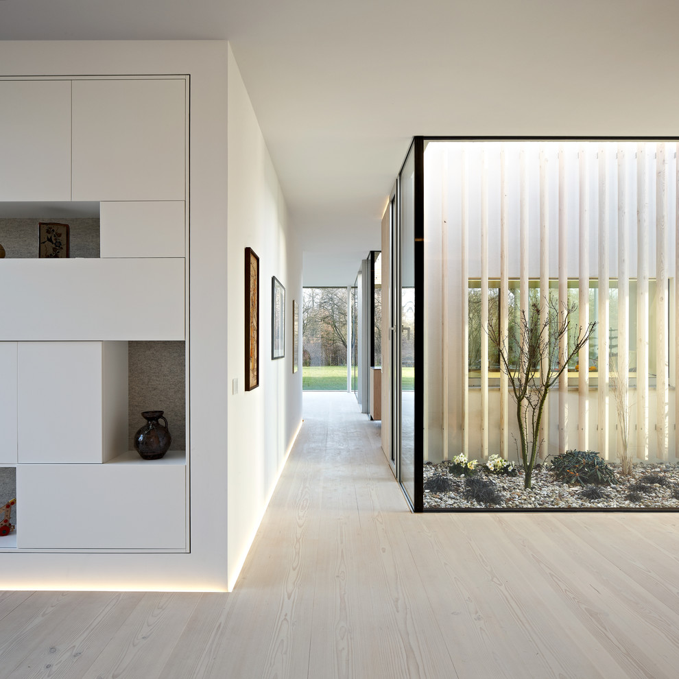 Photo of a large contemporary hallway in Hamburg with light hardwood floors and white walls.