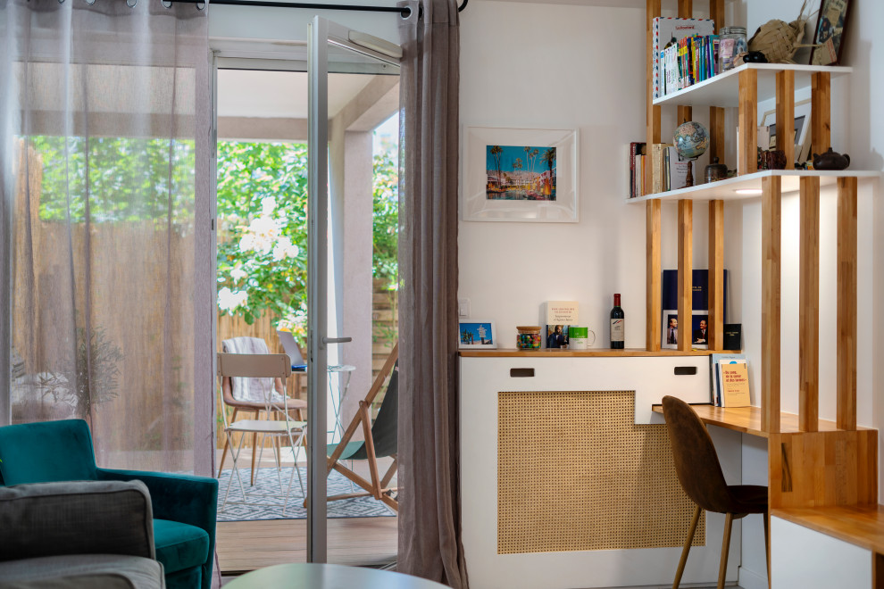 Ejemplo de despacho escandinavo de tamaño medio sin chimenea con biblioteca, paredes blancas, suelo de madera clara, escritorio empotrado y suelo beige