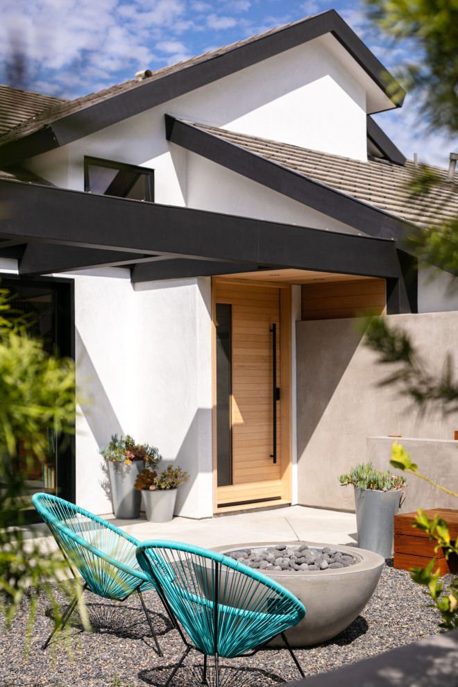 Modelo de puerta principal moderna de tamaño medio con paredes blancas, suelo de cemento, puerta pivotante, puerta de madera clara, suelo gris y madera