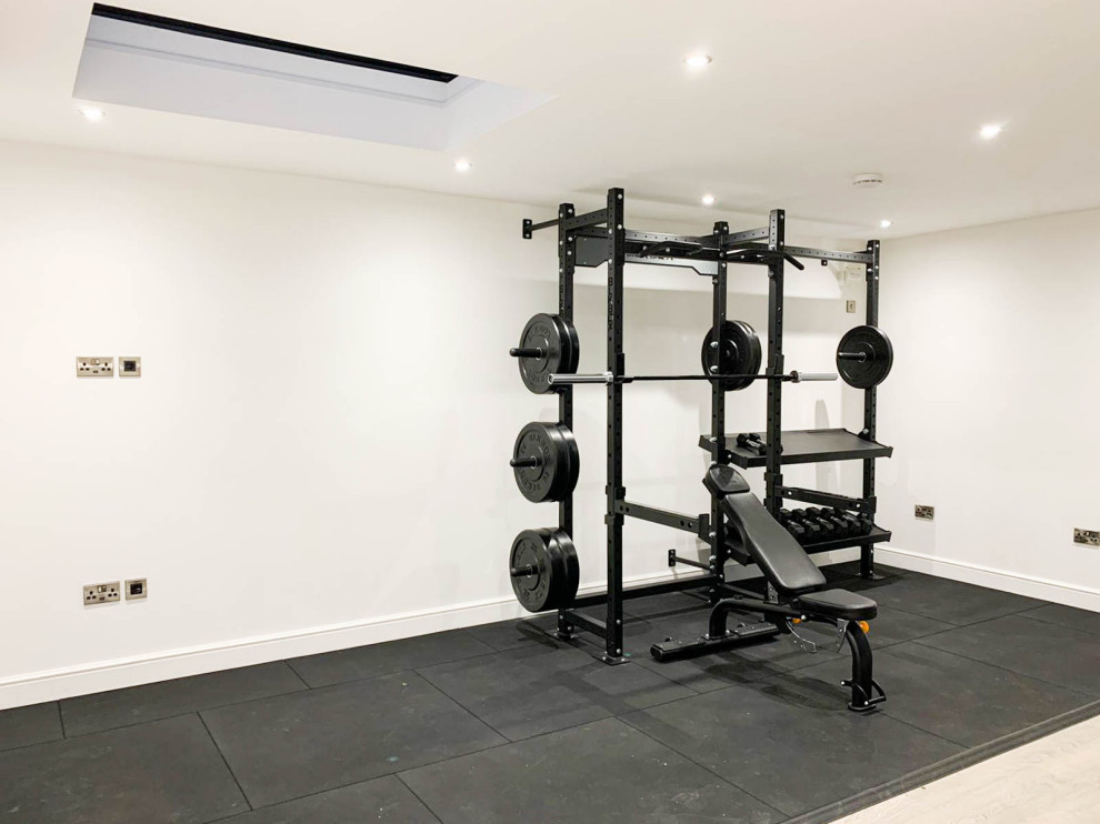 Multifunktionaler, Großer Moderner Fitnessraum mit weißer Wandfarbe, Laminat und braunem Boden in Cheshire