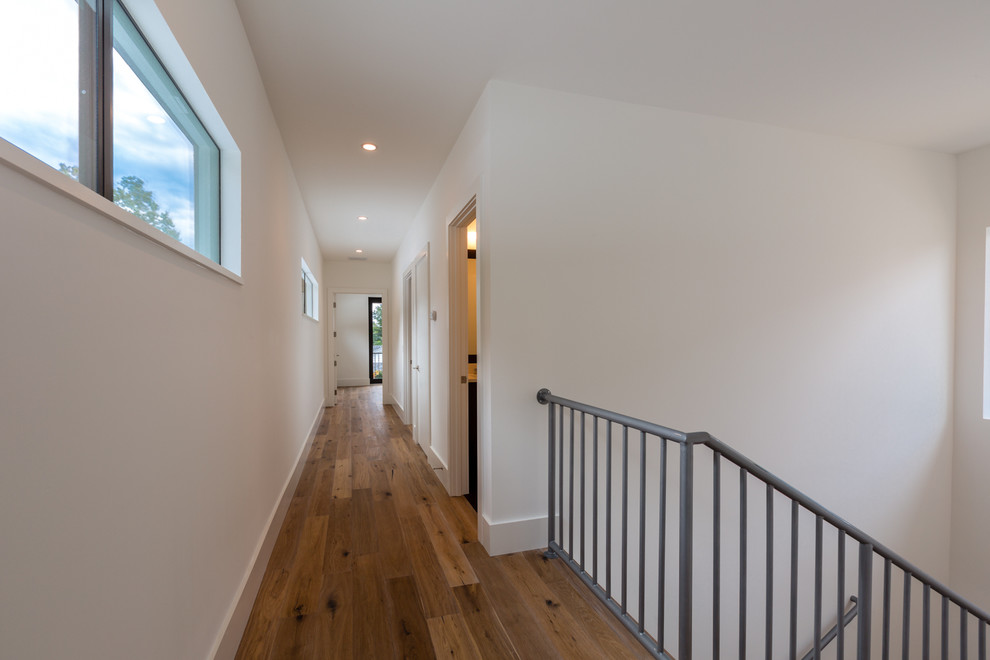 This is an example of a mid-sized modern hallway in Austin with white walls and medium hardwood floors.