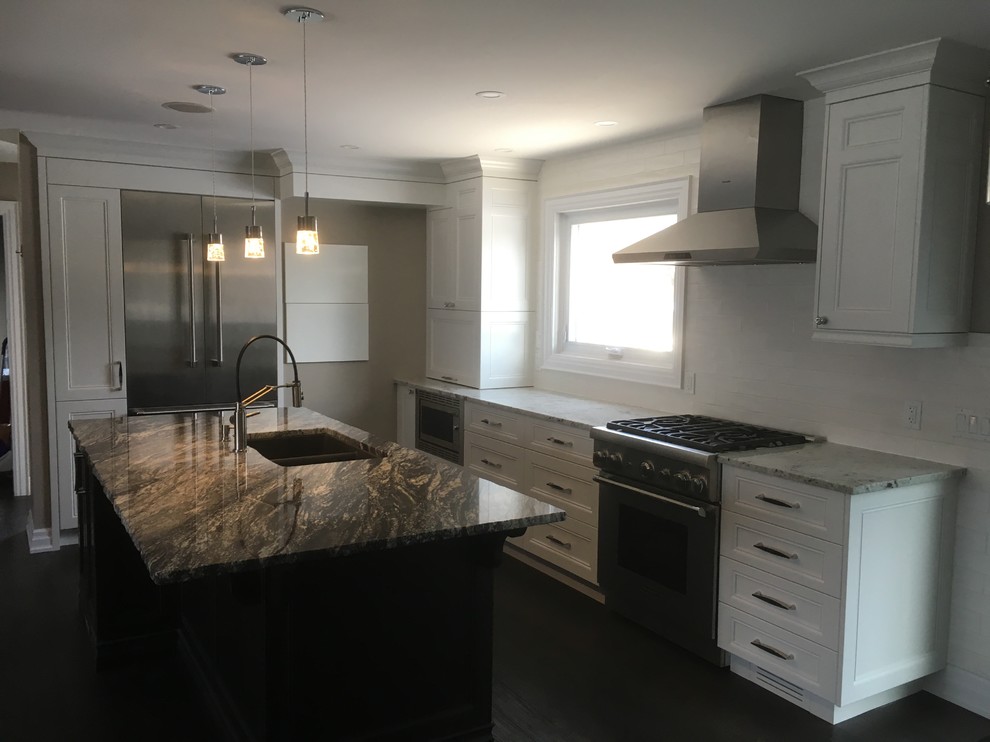 This is an example of a mid-sized transitional l-shaped open plan kitchen in Toronto with a double-bowl sink, recessed-panel cabinets, white cabinets, granite benchtops, white splashback, ceramic splashback, stainless steel appliances, dark hardwood floors, with island, brown floor and grey benchtop.