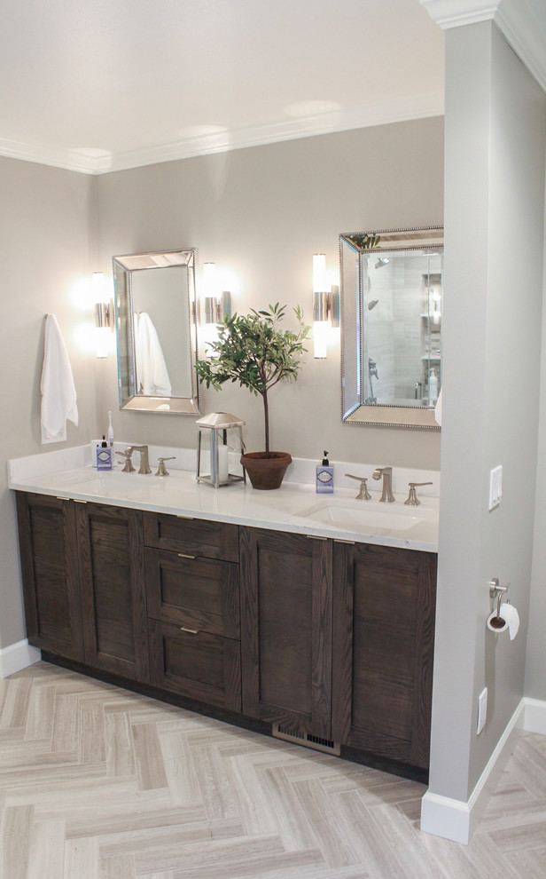 Example of a large transitional master limestone tile limestone floor and beige floor freestanding bathtub design in Denver with brown cabinets, quartz countertops, a hinged shower door, shaker cabinets, gray walls and an undermount sink