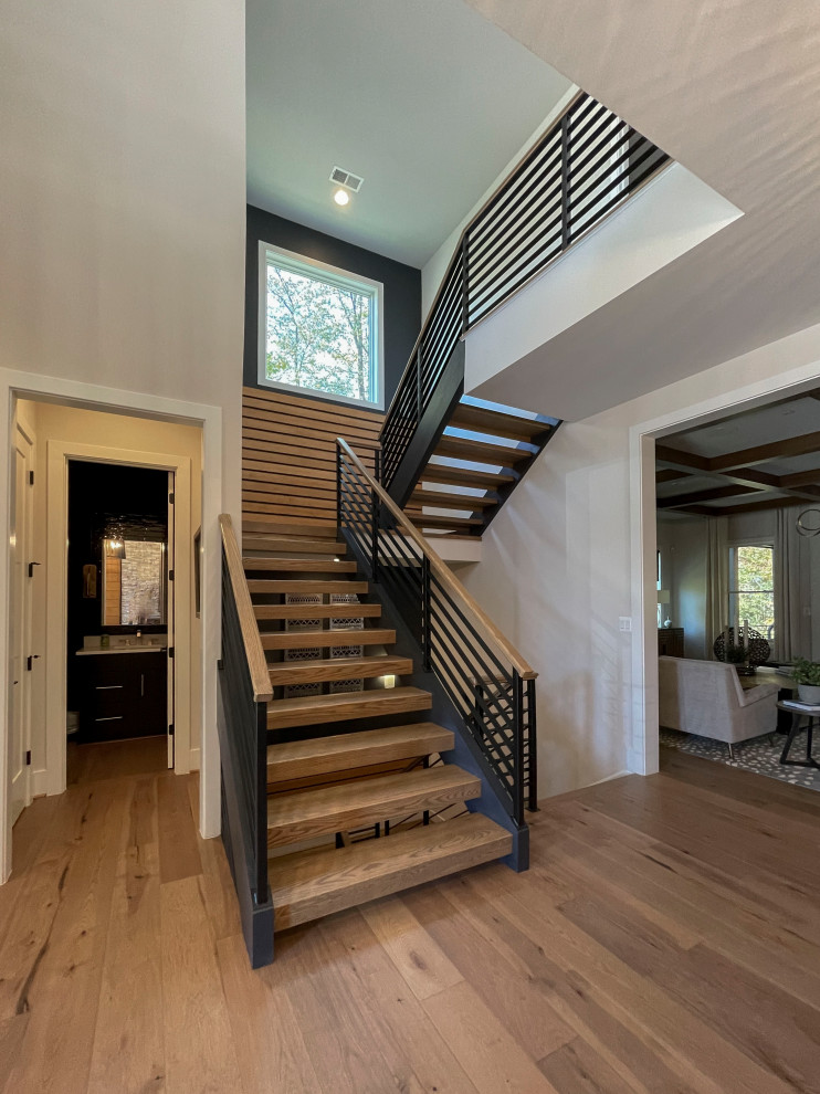 Imagen de escalera recta contemporánea grande con escalones de madera, barandilla de varios materiales y panelado