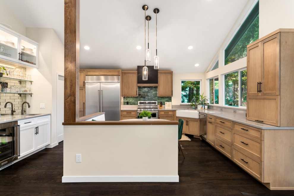 Photo of an industrial u-shaped eat-in kitchen in Seattle with a farmhouse sink, light wood cabinets, quartzite benchtops, green splashback, stainless steel appliances, dark hardwood floors, no island and grey benchtop.