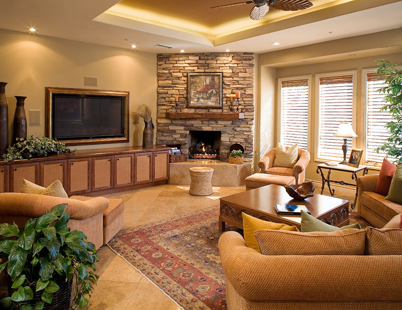 Design ideas for a large tropical family room in San Diego with beige walls, ceramic floors, a corner fireplace, a stone fireplace surround, a wall-mounted tv and brown floor.
