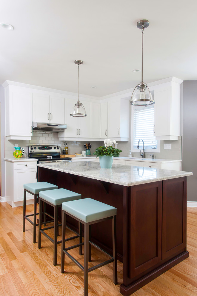 Eat-in kitchen - large transitional u-shaped light wood floor eat-in kitchen idea with an undermount sink, shaker cabinets, white cabinets, granite countertops, gray backsplash, glass tile backsplash, stainless steel appliances and an island