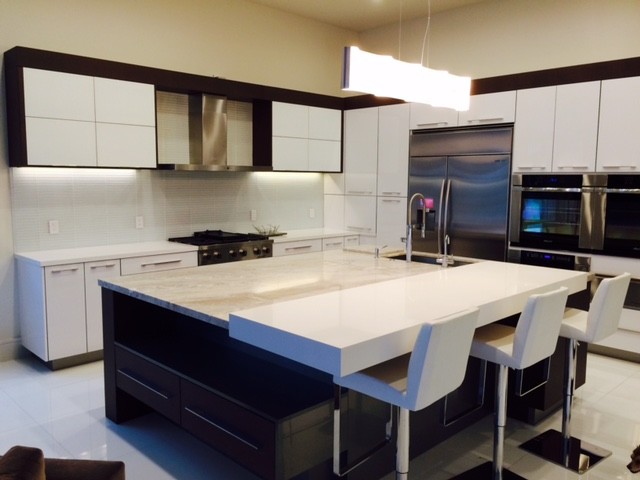 Photo of a large modern l-shaped eat-in kitchen in Miami with an undermount sink, flat-panel cabinets, white cabinets, marble benchtops, white splashback, glass sheet splashback, stainless steel appliances, porcelain floors, with island and white floor.