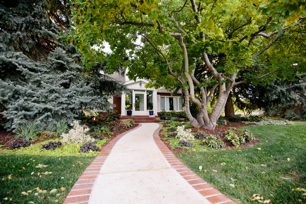 This is an example of a mid-sized traditional front yard partial sun garden in Denver with brick pavers.