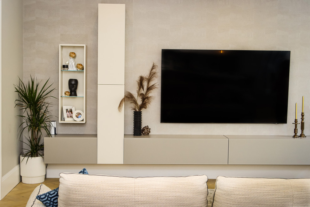 На фото: большая открытая гостиная комната с бежевыми стенами, светлым паркетным полом, телевизором на стене, бежевым полом, обоями на стенах и акцентной стеной с