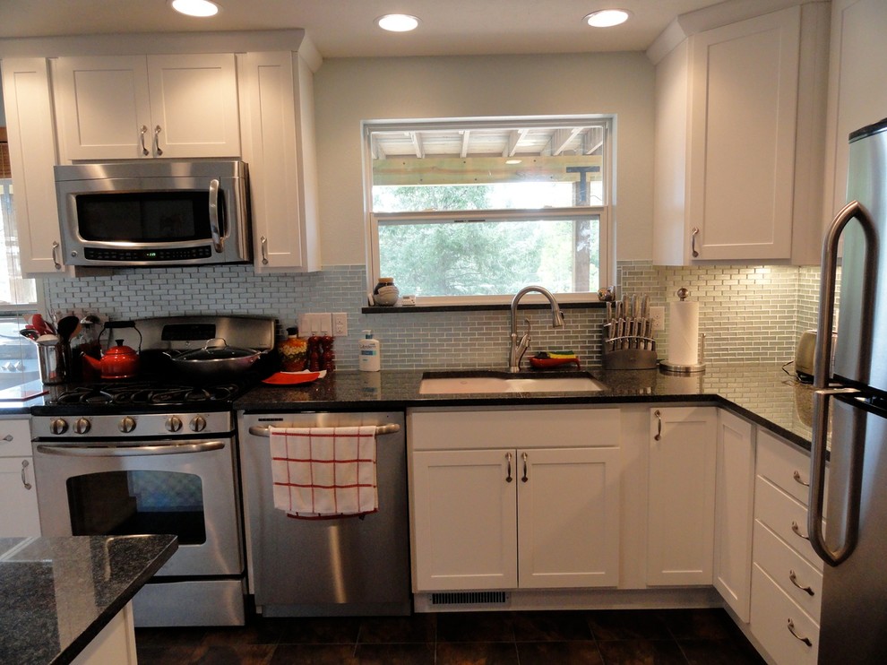 Mid-sized transitional l-shaped porcelain tile and brown floor eat-in kitchen photo in Denver with a double-bowl sink, recessed-panel cabinets, white cabinets, stainless steel appliances, an island, granite countertops, metallic backsplash and metal backsplash
