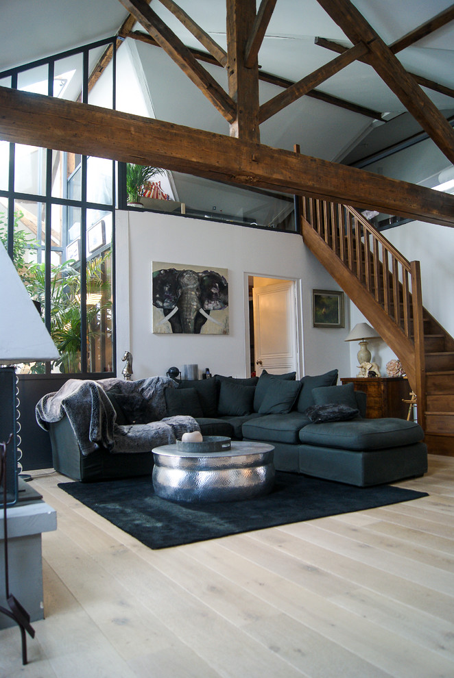 Inspiration pour un grand salon rustique ouvert avec un mur blanc, parquet clair, aucune cheminée, aucun téléviseur et canapé noir.