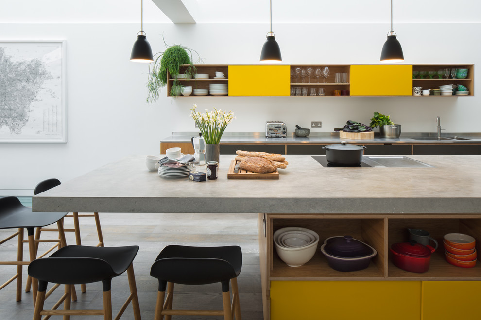 Photo of a contemporary galley kitchen in London with concrete benchtops, with island, a double-bowl sink, flat-panel cabinets, yellow cabinets, grey floor, grey benchtop and light hardwood floors.
