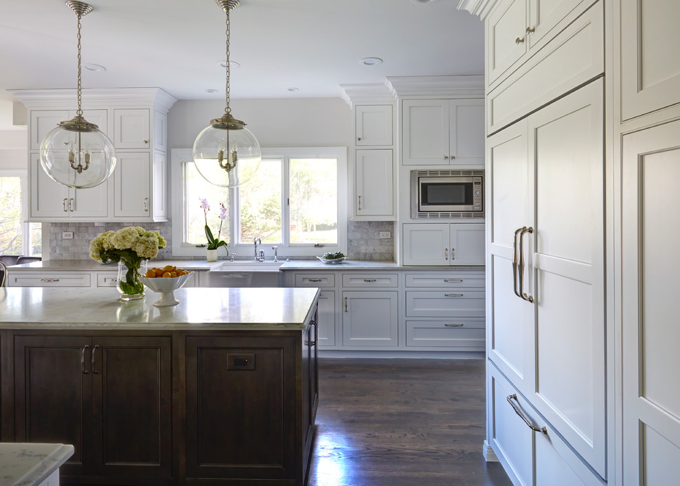 Transitional dark wood floor kitchen photo in Chicago with a farmhouse sink, beaded inset cabinets, white cabinets, quartz countertops, white backsplash, stone tile backsplash, paneled appliances and an island