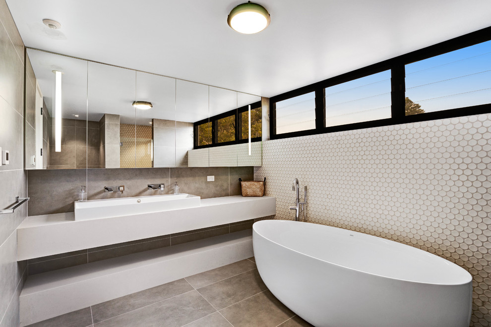 Mid-sized contemporary 3/4 bathroom in Central Coast with a freestanding tub, engineered quartz benchtops, flat-panel cabinets, a trough sink, grey floor and white benchtops.