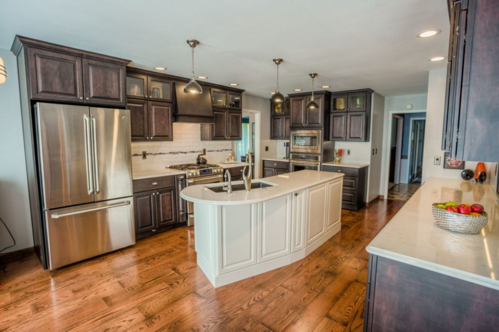 Example of a mid-sized transitional u-shaped light wood floor and brown floor eat-in kitchen design in Raleigh with an undermount sink, shaker cabinets, dark wood cabinets, quartz countertops, multicolored backsplash, ceramic backsplash, stainless steel appliances, an island and white countertops