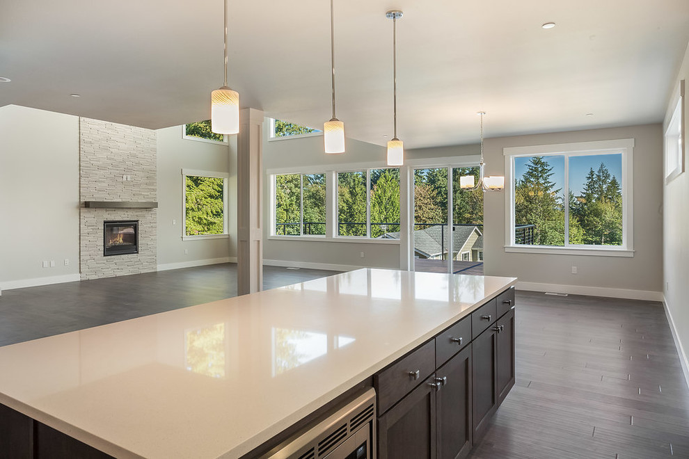 This is an example of a contemporary l-shaped open plan kitchen in Seattle with a submerged sink, shaker cabinets, white cabinets, quartz worktops, grey splashback, metro tiled splashback, stainless steel appliances, dark hardwood flooring, an island, brown floors and white worktops.