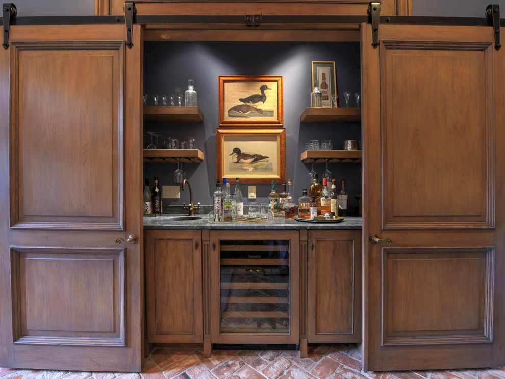 Design ideas for a large traditional single-wall wet bar in New Orleans with an undermount sink, recessed-panel cabinets, medium wood cabinets, marble benchtops, brick floors and brown floor.
