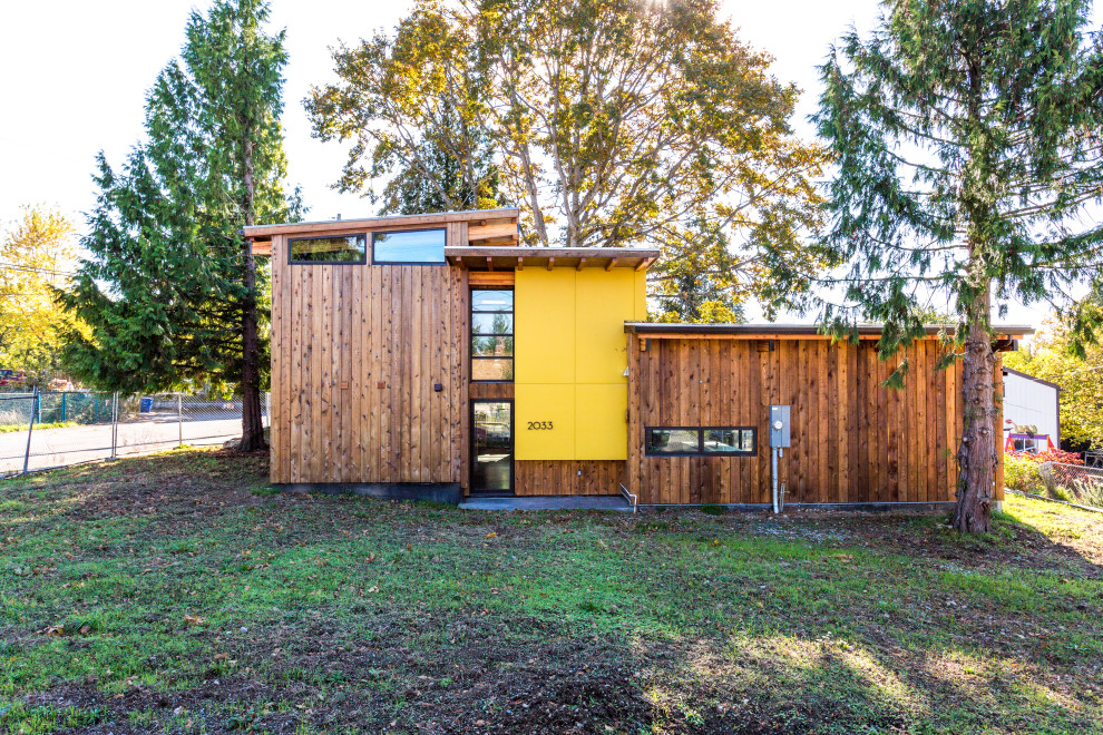 Idee per la facciata di una casa gialla moderna a due piani di medie dimensioni con tetto bianco, pannelli e listelle di legno e rivestimenti misti