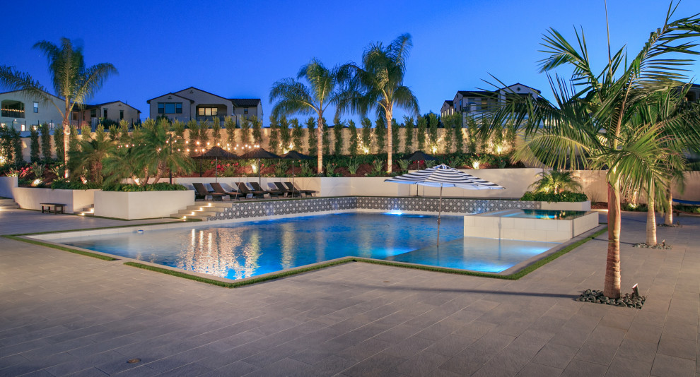 Immagine di una grande piscina minimal rettangolare dietro casa con una vasca idromassaggio e piastrelle