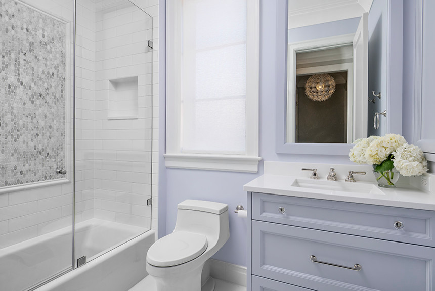 This is an example of a small transitional kids bathroom in Chicago with recessed-panel cabinets, purple cabinets, an alcove tub, a shower/bathtub combo, a one-piece toilet, white tile, marble, purple walls, porcelain floors, an undermount sink and engineered quartz benchtops.