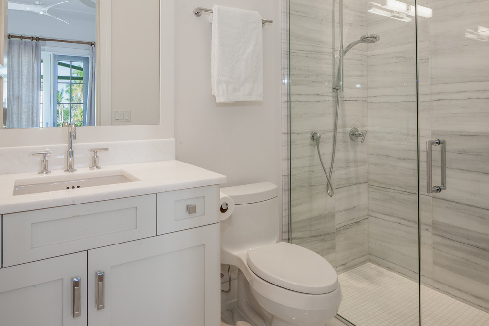 Design ideas for a small beach style 3/4 bathroom in Miami with shaker cabinets, white cabinets, a freestanding tub, white tile, white walls, porcelain floors, an undermount sink, marble benchtops, white floor and a hinged shower door.
