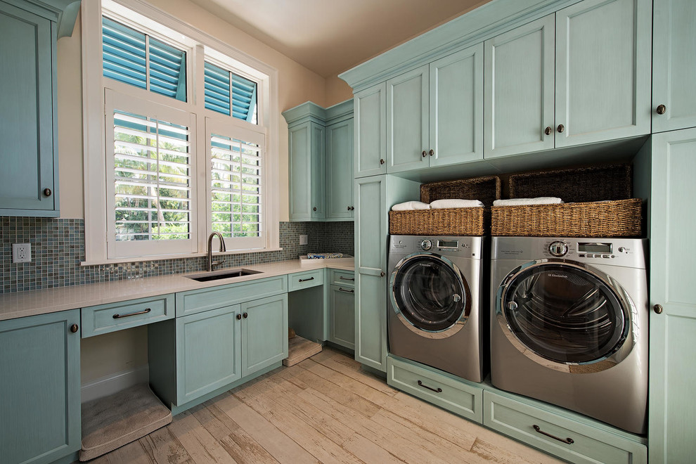 Large transitional l-shaped dedicated laundry room in Miami with an undermount sink, shaker cabinets, blue cabinets, quartzite benchtops, beige walls, light hardwood floors and a side-by-side washer and dryer.
