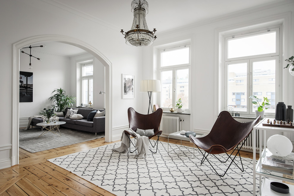 This is an example of a large scandinavian formal open concept living room in Stockholm with white walls, medium hardwood floors, no fireplace and brown floor.