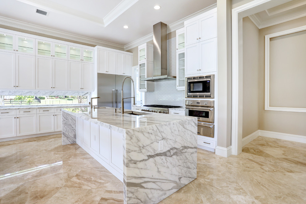 Design ideas for a large modern l-shaped open plan kitchen in Miami with an undermount sink, shaker cabinets, white cabinets, marble benchtops, stainless steel appliances, limestone floors, with island and beige floor.
