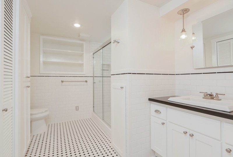 Transitional master white tile white floor corner shower photo in Denver with shaker cabinets, white cabinets, white walls and a drop-in sink