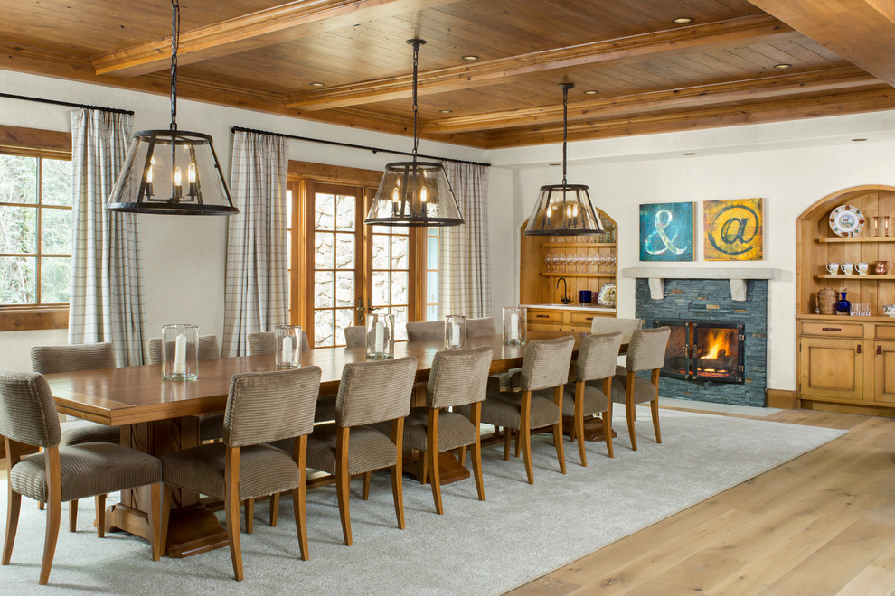 Photo of a country dining room in Denver with white walls, light hardwood floors and a standard fireplace.