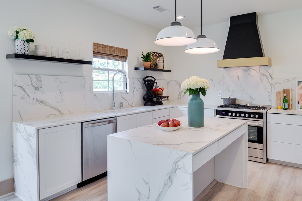 Open concept kitchen - mid-sized transitional l-shaped light wood floor open concept kitchen idea in Orange County with an undermount sink, flat-panel cabinets, white cabinets, marble countertops, white backsplash, marble backsplash, stainless steel appliances and an island